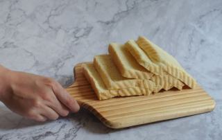 Tranche de pain maison à la mie serrée posée sur une planche en bois