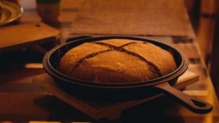 Miche ronde dorée sortant d'une cocotte en fonte